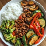 Spicy beef stir-fry bowl with garlic vegetables and steamed rice